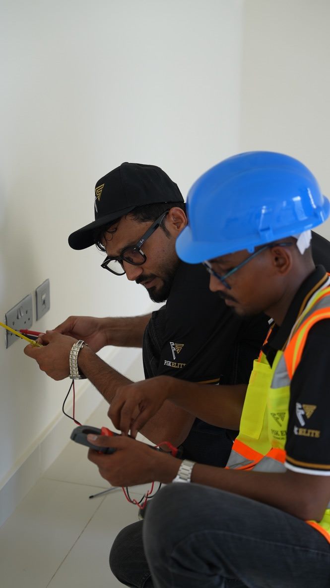 FSK Elite electricians testing a wall socket in a Dubai home